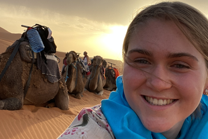 UMD study abroad student in Morocco in front of camels
